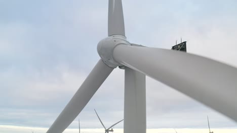 Nahaufnahme-Einer-Windkraftanlage-In-Finnland-Mit-Einem-Windpark-Im-Hintergrund,-Enthüllungsaufnahme