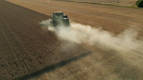 Niedrige-Drohnenaufnahme-Des-Grünen-John-Deere-Mähdreschers-Im-Staub-In-Die-Sonne-Großbritannien