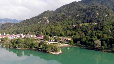 Schnelle-Enthüllung-Von-Luftaufnahmen-Des-Dorfes-Barcis-In-Den-Dolomiten-Dolomiten-Norditalien-Mit-Einem-Großen-Blaugrünen-See-Und-Einem-Kleinen-Reflektierenden-Boot