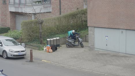 Mensajero-De-Entrega-De-Deliveroo-Que-Sale-De-La-Ubicación-Del-Cliente-Después-De-Dejar-El-Pedido-De-Comida-En-La-Puerta-Principal---Bruselas,-Bélgica