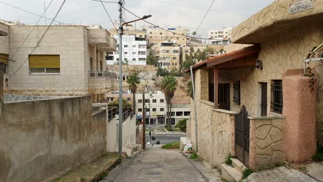 Built-up-houses-in-densely-populated-Capital-city-of-Amman-in-Jordan,-view-of-alleyway-with-steps,-buildings-and-traffic