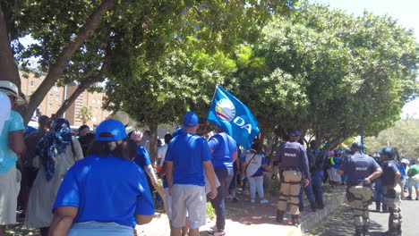 Una-Toma-De-Seguimiento-Inverso-De-Un-Manifestante-Que-Sostiene-Una-Bandera-Del-Partido-De-La-Alianza-Democrática-En-Una-Marcha-Contra-Los-Cortes-De-Carga-Y-Los-Apagones-Continuos-De-Eskom