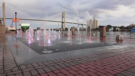 Rote-Backsteine-Und-Der-Brunnen,-Der-Buntes-Wasser-Ausstrahlt,-Im-Werksviertel-Am-Fluss