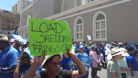 A-Coloured-woman-holds-up-a-sign-associating-rolling-blackouts-with-crime