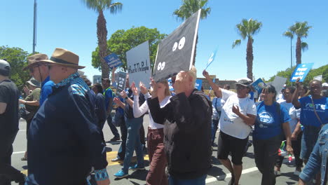 Two-women-holding-up-protest-signs-during-a-peaceful-march-against-load-shedding-and-rolling-blackouts-in-Cape-Town,-South-Africa