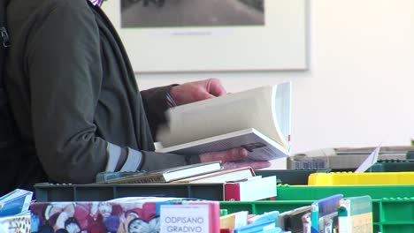 close-up-of-person-holding-a-book-at-fair-in-library-checking-for-title