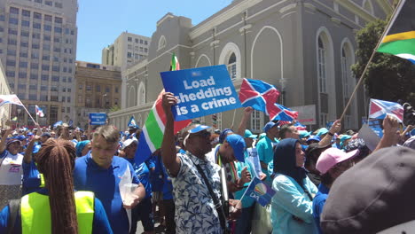 A-diverse-crowd-of-peaceful-protestors-listens-to-an-engaging-speech-by-a-politician-about-Eskom's-load-shedding-and-rolling-blackouts