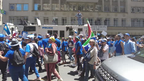 A-policeman-standing-on-the-roof-of-a-riot-vehicle-watches-over-a-stream-of-protestors-marching-against-Eskom's-load-shedding-and-rolling-blackouts