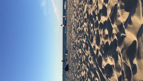 Vertikales-Video-Vom-Strand-Der-Westerplatte-In-Der-Nähe-Von-Danzig-In-Polen-Mit-Menschen,-Die-Sich-Entspannen-Und-Bei-Sonnenuntergang-Laufen