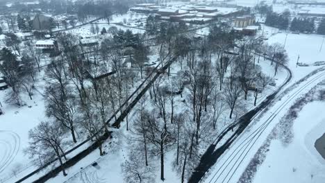 High-aerial-orbit-around-snow-covered-park-in-winter