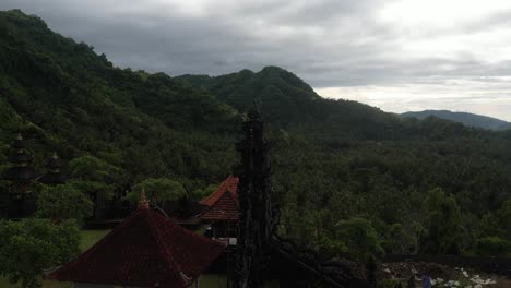 Orbiting-shot-of-Ornamented-tower-in-Buddhist-temple-in-Bali,-forested-mountains-in-Background