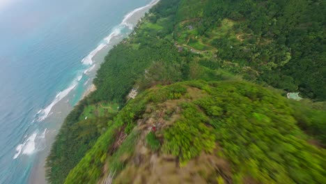 Aerial-drone-shot-of-the-top-of-a-high-sharp-mountain-peaks-revealing-tropical-coastline,-Na-Pali-park-Kauai