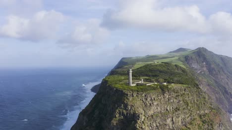 drone-footage-of-a-Lighthouse-on-the-edge-of-dramatic-cliffs-with-the-Atlantic-Ocean-in-the-background,-São-Jorge-island,-the-Azores,-Portugal