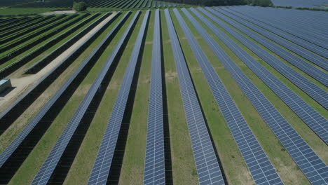 Establishing-Drone-Shot-Flying-Down-Side-of-Field-of-Solar-Panels-on-Solar-Farm-on-Bright-Sunny-Day