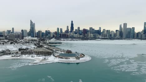 Aerial-view-over-the-Adler-Planetarium-towards-the-Chicago-cityscape,-gloomy,-winter-evening-in-Illinois,-USA