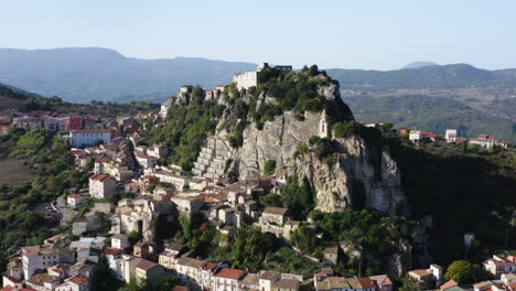 Fly-away-aerial-shot-of-Bagnoli-del-Trigno-town-with-San-Silvestro-church-between-two-rock-spurs,-Isernia-and-Molise-region,-Italy,-4K