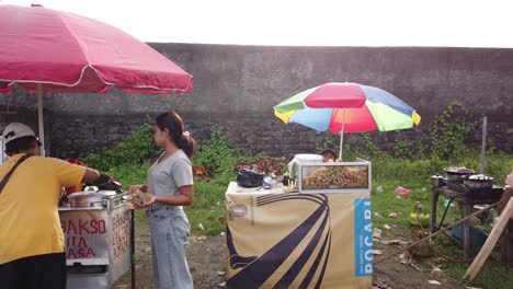 Street-Food-Sellers-in-Bali-Beach,-Bakso-and-Fried-Snacks-Indonesia-Local-Market-Traditional-Umbrellas-and-People-Buying-in-Sukawati,-Purnama,-Gianyar