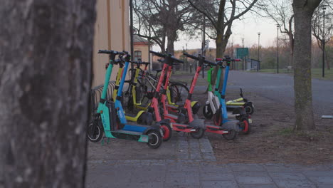 Group-of-parked-electric-scooters-for-rent,-in-Stockholm,-wide,-handheld