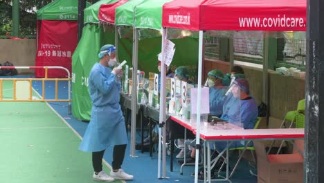 Los-Trabajadores-De-La-Salud-Que-Usan-Trajes-De-Ppe-Son-Vistos-En-Una-Instalación-De-Prueba-Temporal-Fuera-De-Un-Edificio-Cerrado-Después-De-Que-Una-Gran-Cantidad-De-Residentes-Dieron-Positivo-En-El-Coronavirus-Covid-19