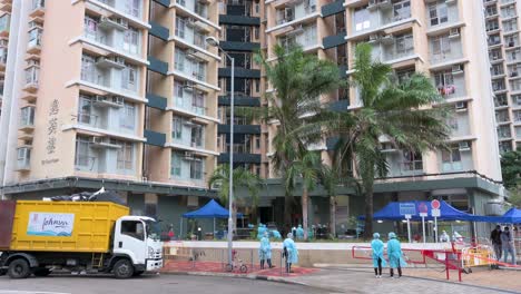 Se-Ve-A-Los-Trabajadores-De-La-Salud-Y-A-Los-Policías-Con-Trajes-De-Protección-Personal-Parados-Vigilantes-Fuera-De-Un-Edificio-Cerrado-Después-De-Que-Un-Gran-Número-De-Residentes-Dieron-Positivo-En-El-Coronavirus-Covid-19