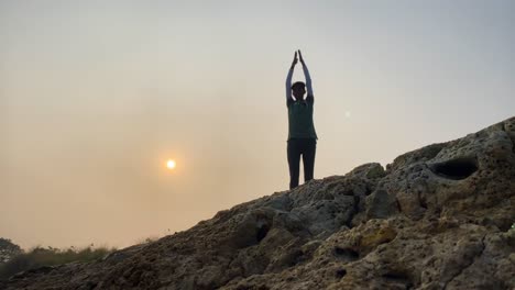 Static-wide-view-of-man-exercising-stretching-outdoor,-rocky-landscape,-sunrise,-morning