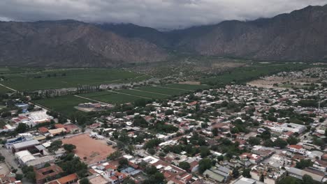 Cafayate-Town,-Salta,-Argentina,-Aerial-Drone-View-of-Vineyard-Valley-Calchaqui,-Old-City-and-Andean-Cordillera-Mountain-Range-in-the-Background,-South-America
