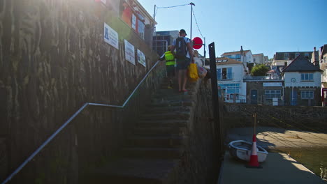 Father-And-Child-Climbing-On-The-Steps-Of-St-Mawes-Harbor,-Cornwall,-United-Kingdom