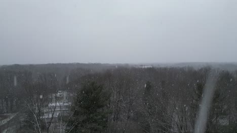 Crane-Shot-Of-High-Rise-Green-Trees-Under-Snowflakes,-Warren,-Ohio,-USA