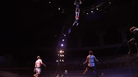 Cirque-du-Soleil:-Professional-circus-athletes-practicing-and-rehearsing-trampoline-act-in-a-stunning-dimmed-light-venue,-man-falling-from-trapeze