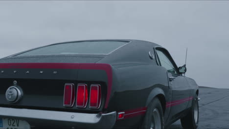 Parte-Trasera-Del-Coche-Deportivo-Clásico-Ford-Mustang-Mach-1-Moviéndose-En-Carretera-Mojada-Y-Día-Lluvioso