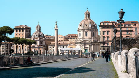 Lapso-De-Tiempo-De-Peatones-Caminando-Por-Las-Calles-De-La-Ciudad-De-Roma-Con-La-Iglesia-Católica,-Chiesa-Del-Santissimo-Nome-Di-Maria-Al-Foro-Traiano,-De-Pie-De-Manera-Prominente-En-El-Fondo