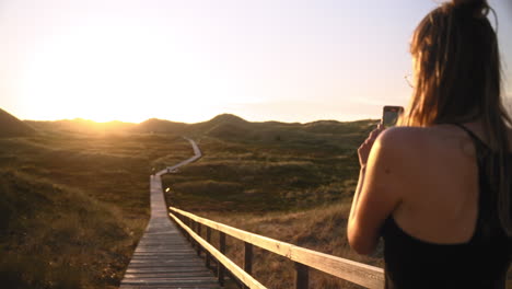 Slow-motion:-Woman-takes-video-of-sunset-at-a-dune