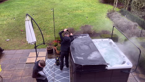 Two-cleaners-clean-and-service-a-hot-tub-for-maintenance-in-the-back-garden-of-a-house-in-the-UK