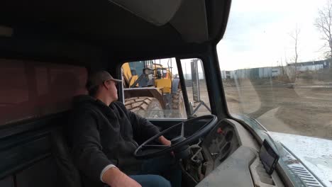 Heavy-tractor-loading-vintage-dump-truck-while-driver,-interior-view