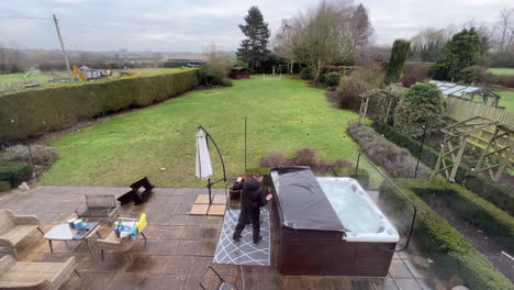 Two-cleaners-clean-and-service-a-hot-tub-for-maintenance-in-the-back-garden-of-a-house-in-the-UK
