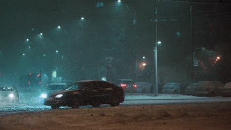 Car-driving-away-in-the-city-on-a-frosty-winter-night,-during-a-blizzard,-super-slow-motion,-teal-and-orange-colors