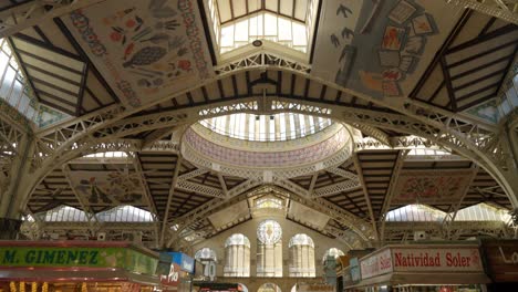 Wide-angle-view-of-famous-Central-Valencia-Marketplace,-Spain,-Pan-up-showing-decorated-ceiling