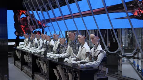 Eine-Reihe-Von-Humanoiden-Robotern,-Die-Vor-Einem-Langen-Tisch-Sitzen-Und-Auf-Einen-Sanften-Monsterladen-In-Starfield-Hanam-Blicken