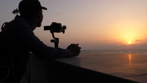 Silueta-De-Fotógrafo-Y-Cámara-Dslr-Filmando-Puesta-De-Sol-Naranja-Sobre-El-Océano