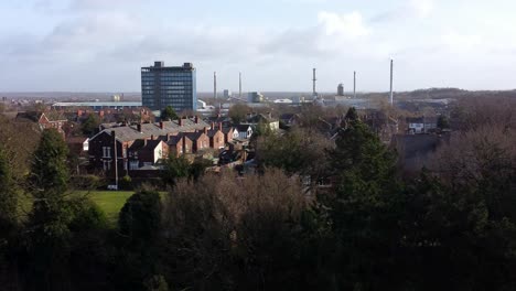 Luftaufnahme-über-Parkbäume-Zum-Industriellen-Stadtbild-Mit-Blauem-Wolkenkratzer,-Merseyside,-England