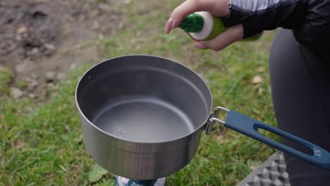 Ölen-Des-Topfes-Auf-Dem-Feldkocher-Am-Ufer-Des-Sees-Während-Eines-Tages,-Essenszubereitung