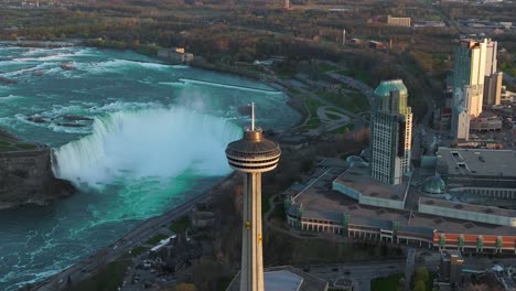 Cataratas-Del-Niágara-Desde-El-Lado-De-Canadá-Con-Torre-De-Observación-Durante-La-Puesta-De-Sol,-Drones-En-órbita