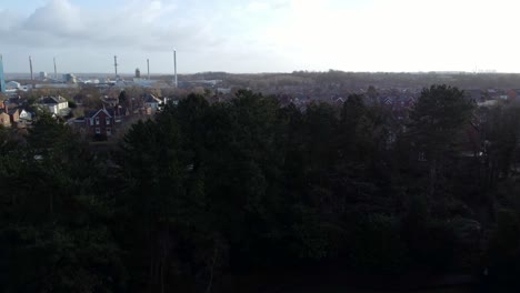 Luftaufnahme,-Die-über-Parkbäume-Zum-Industriellen-Stadtbild-Mit-Blauem-Wolkenkratzer,-Merseyside,-England-Schwenkt