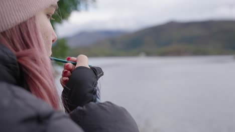 eating-the-prepared-food-on-field-cooker-at-the-bank-of-the-loch-during-a-day,-food-preparation