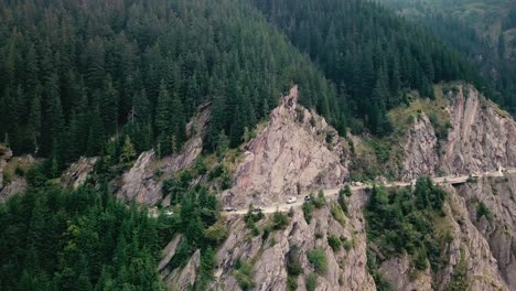 Crane-down-drone-shot-of-a-mountain-road-next-to-a-cliff