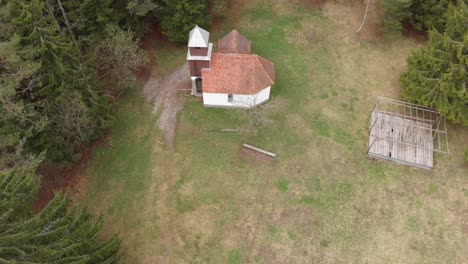 Aerial-view-of-an-old-church-in-the-middle-of-a-pine-forest-in-Romania