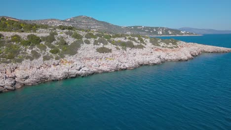 Slow-forward-drone-shot-towards-a-rocky-shore-with-more-gulfs-at-the-background-over-the-aegean-sea,-Greece