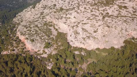 Sideways-aerial-shot-of-rocky-cliffs-inside-a-forest