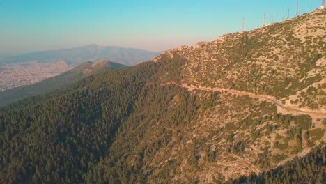 Crane-up-aerial-shot-of-Ymittos-mountain-next-to-Athens,-Greece-during-golden-hour