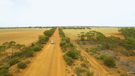 4WD-travelling-on-a-remote-red-dusty-road,-aerial-follow-shot